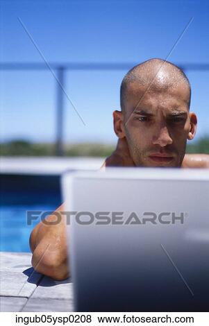 Young man in a swimming pool using a laptop View Large Photo Image Stock Photo - Young man in a swimming pool using a laptop. Fotosearch