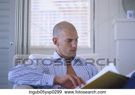 Stock Photo - Young man sitting in a chair and reading a file. Fotosearch