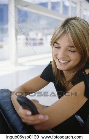 Young woman using a mobile phone and smiling View Large Photo Image Stock Photo - Young woman using a mobile phone and smiling. Fotosearch