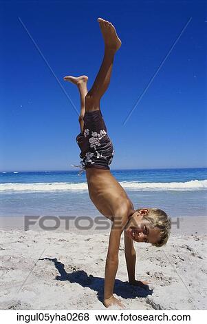 Stock Photo - Boy doing a handstand on the beach. Fotosearch