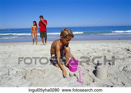 Stock Image - Boy playing in the sand on the beach. Fotosearch