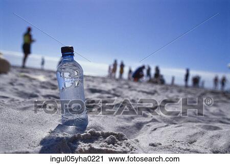 Stock Image - Close-up of a bottle of water on the beach. Fotosearch