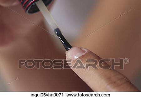 Stock Image - Close-up of a person applying nail polish. Fotosearch