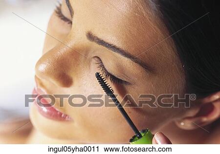 Close-up of a young woman applying make-up View Large Photo Image Stock Image - Close-up of a young woman applying make-up. Fotosearch