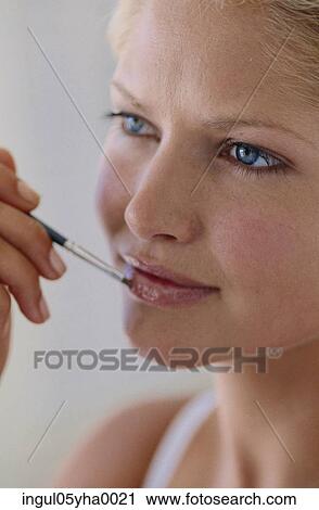 Close-up of a young woman applying make-up View Large Photo Image Stock Image - Close-up of a young woman applying make-up. Fotosearch