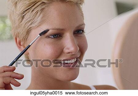Close-up of a young woman applying make-up View Large Photo Image Stock Photography - Close-up of a young woman applying make-up. Fotosearch