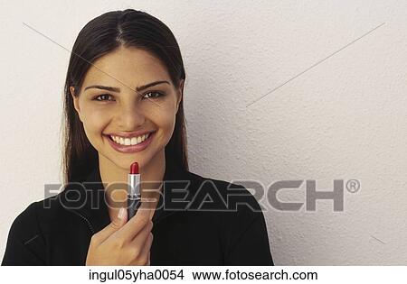 Picture - Close-up of a young woman holding lipstick. Fotosearch