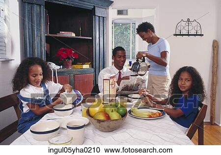 Stock Image - Family sitting at a dining table. Fotosearch