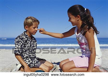 Girl applying cream on a boy's face View Large Photo Image Stock Photo - Girl applying cream on a boy's face. Fotosearch