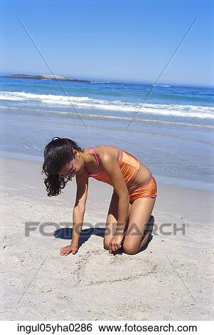Girl drawing in the sand on the beach View Large Photo Image Stock Photograph - Girl drawing in the sand on the beach. Fotosearch