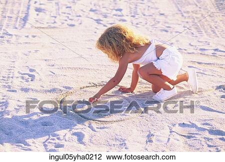 Stock Image - Girl drawing in the sand. Fotosearch