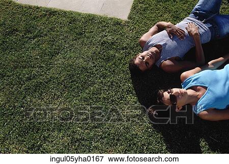 Stock Photo - High angle view of a young couple lying on a lawn. Fotosearch