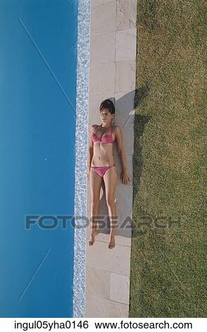 High angle view of a young woman lying beside a swimming pool View Large Photo Image Stock Photograph - High angle view of a young woman lying beside a swimming pool. Fotosearch