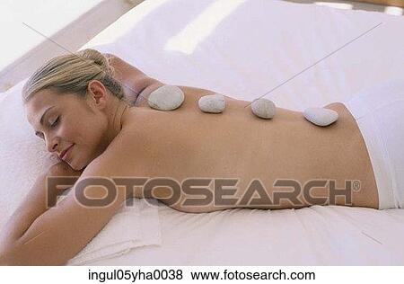 Stock Photo - High angle view of a young woman with therapeutic stones on her back. Fotosearch