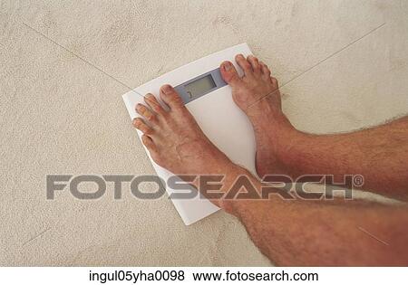 Low section view of a person standing on a weighing scale View Large Photo Image Stock Photo - Low section view of a person standing on a weighing scale. Fotosearch