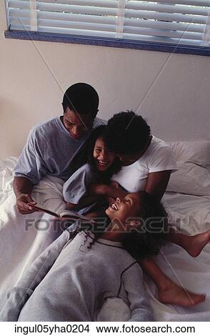 Parents on a bed with their two daughters View Large Photo Image Picture - Parents on a bed with their two daughters. Fotosearch