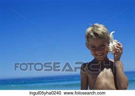 Portrait of a boy holding a conch shell against his ear View Large Photo Image Stock Image - Portrait of a boy holding a conch shell against his ear. Fotosearch