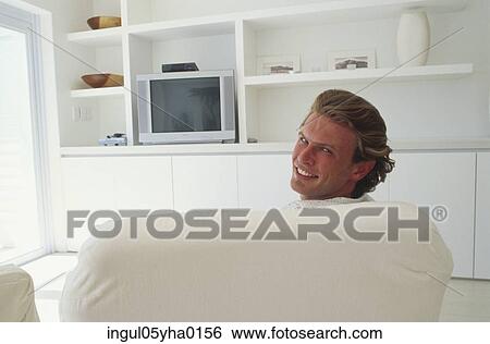 Portrait of a young man sitting on a couch View Large Photo Image Stock Photograph - Portrait of a young man sitting on a couch. Fotosearch