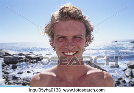 Portrait of a young man standing on the beach View Large Photo Image Stock Image - Portrait of a young man standing on the beach. Fotosearch