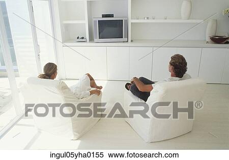 Rear view of a young couple watching television View Large Photo Image Stock Photography - Rear view of a young couple watching television. Fotosearch
