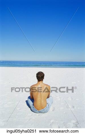 Rear view of a young man sitting on the beach View Large Photo Image Stock Image - Rear view of a young man sitting on the beach. Fotosearch