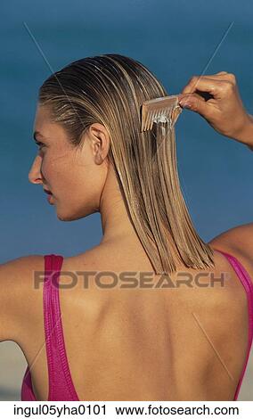 Rear view of a young woman combing her hair View Large Photo Image Stock Image - Rear view of a young woman combing her hair. Fotosearch