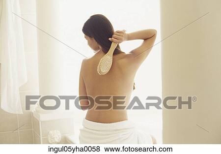 Stock Photo - Rear view of a young woman scrubbing her back. Fotosearch
