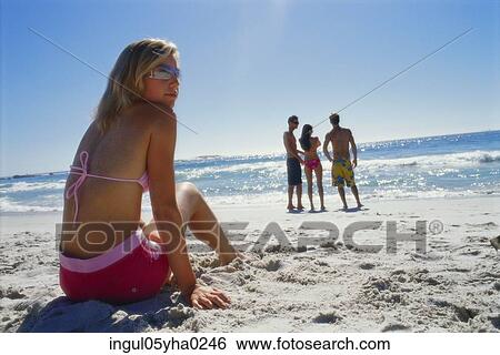 Rear view of a young woman sitting on the beach View Large Photo Image Stock Photograph - Rear view of a young woman sitting on the beach. Fotosearch