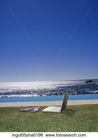 Stock Photograph - Slippers and a laptop on a lawn. Fotosearch