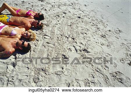 Picture - Two young couples lying on the beach. Fotosearch