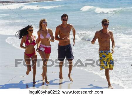 Stock Image - Two young couples running on the beach. Fotosearch