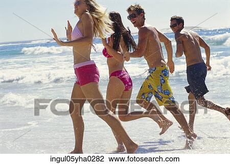 Stock Image - Two young couples running on the beach. Fotosearch