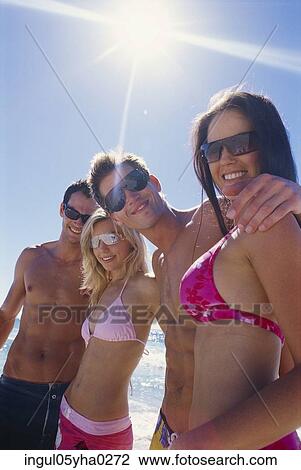 Stock Image - Two young couples standing in a row on the beach. Fotosearch