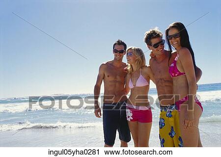 Stock Image - Two young couples standing in a row on the beach. Fotosearch