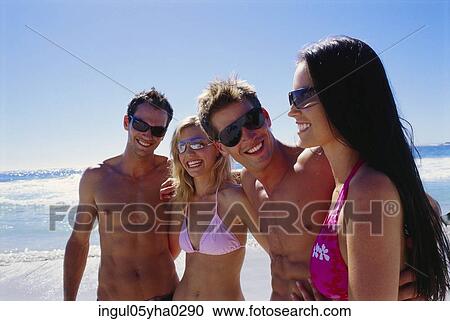 Stock Image - Two young couples standing on the beach. Fotosearch