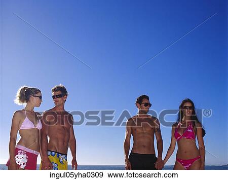 Two young couples standing on the beach View Large Photo Image Stock Photo - Two young couples standing on the beach. Fotosearch