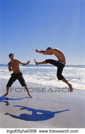 Stock Photo - Two young men playing on the beach. Fotosearch