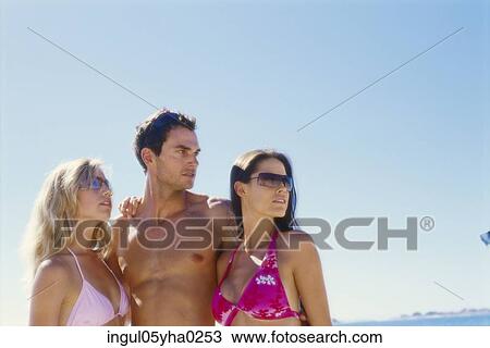 Two young women and a young man standing on the beach View Large Photo Image Stock Image - Two young women and a young man standing on the beach. Fotosearch