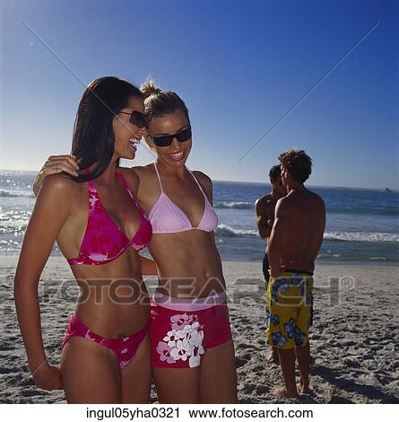 Stock Image - Two young women standing on the beach. Fotosearch