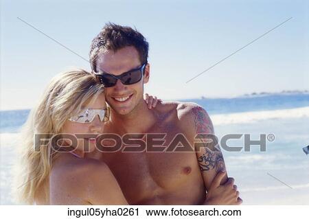 Young couple holding each other on the beach View Large Photo Image Stock Image - Young couple holding each other on the beach. Fotosearch