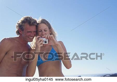 Stock Photography - Young couple looking at a camera. Fotosearch
