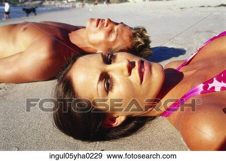 Young couple lying down on the beach View Large Photo Image Stock Photo - Young couple lying down on the beach. Fotosearch