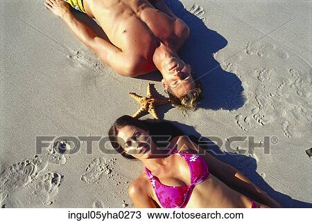 Stock Image - Young couple lying on the beach. Fotosearch