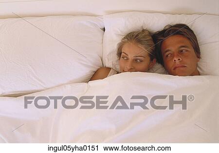 Stock Image - Young couple lying together in bed. Fotosearch