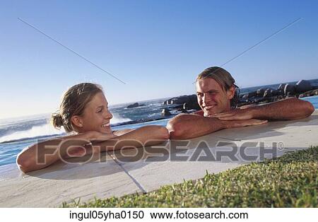 Stock Image - Young couple together in a swimming pool. Fotosearch