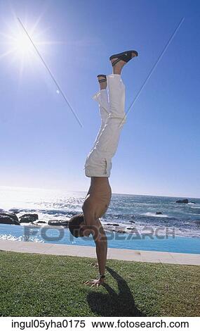 Young man doing a handstand on the lawn View Large Photo Image Stock Photography - Young man doing a handstand on the lawn. Fotosearch