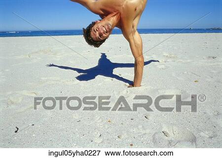 Young man doing a one arm handstand on the beach View Large Photo Image Stock Photo - Young man doing a one arm handstand on the beach. Fotosearch