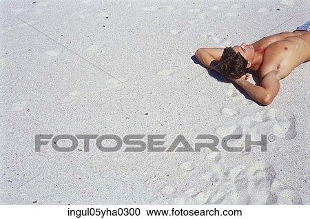 Stock Image - Young man lying on the beach. Fotosearch