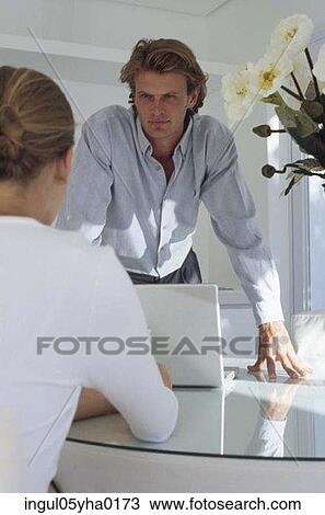 Stock Image - Young man standing in front of a young woman. Fotosearch