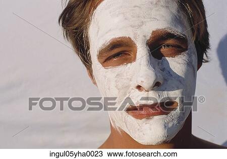 Stock Image - Young man wearing a face pack. Fotosearch